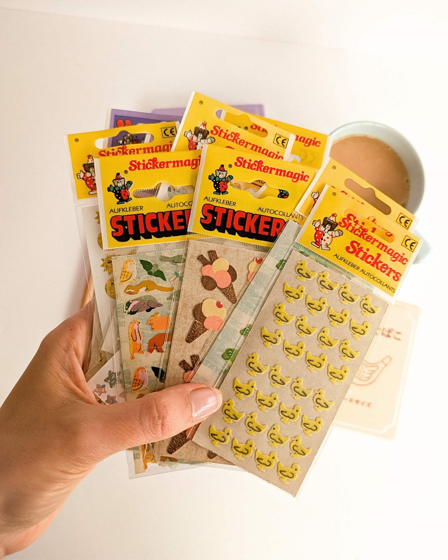 Hand holding a collection of Stickermagic stickers with colorful packaging.