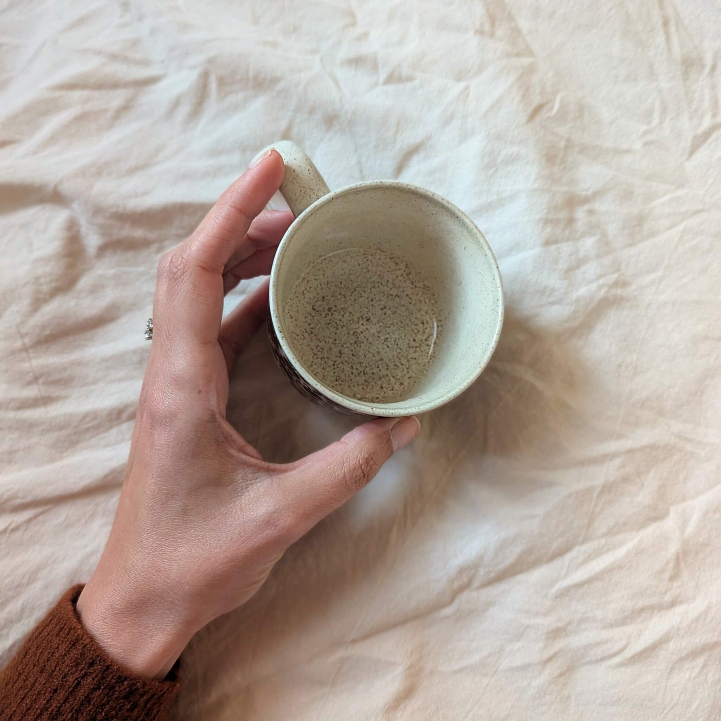 The top down view of a vintage, ceramic teacup. Cream glaze with brown specks.