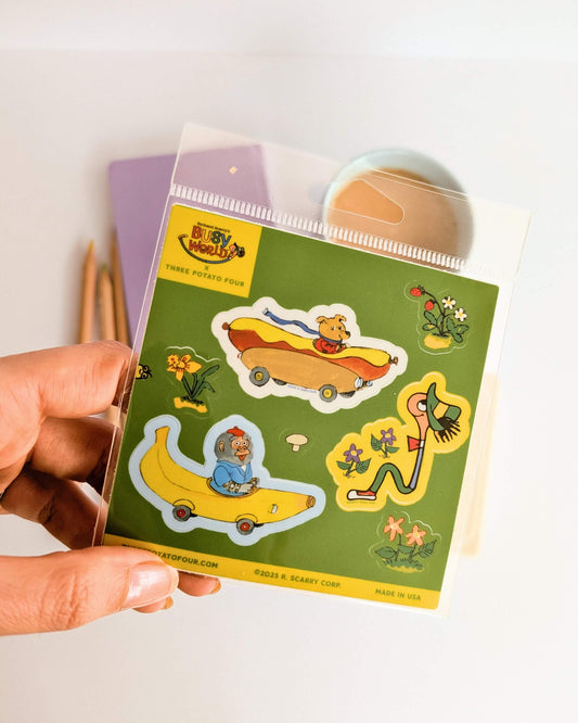 Hand holding a pack of colorful stickers with richard scarry designs on a light background