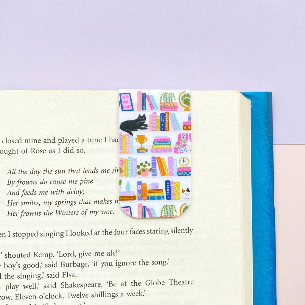 Open book with a colorful bookmark featuring books and a cat on a purple background