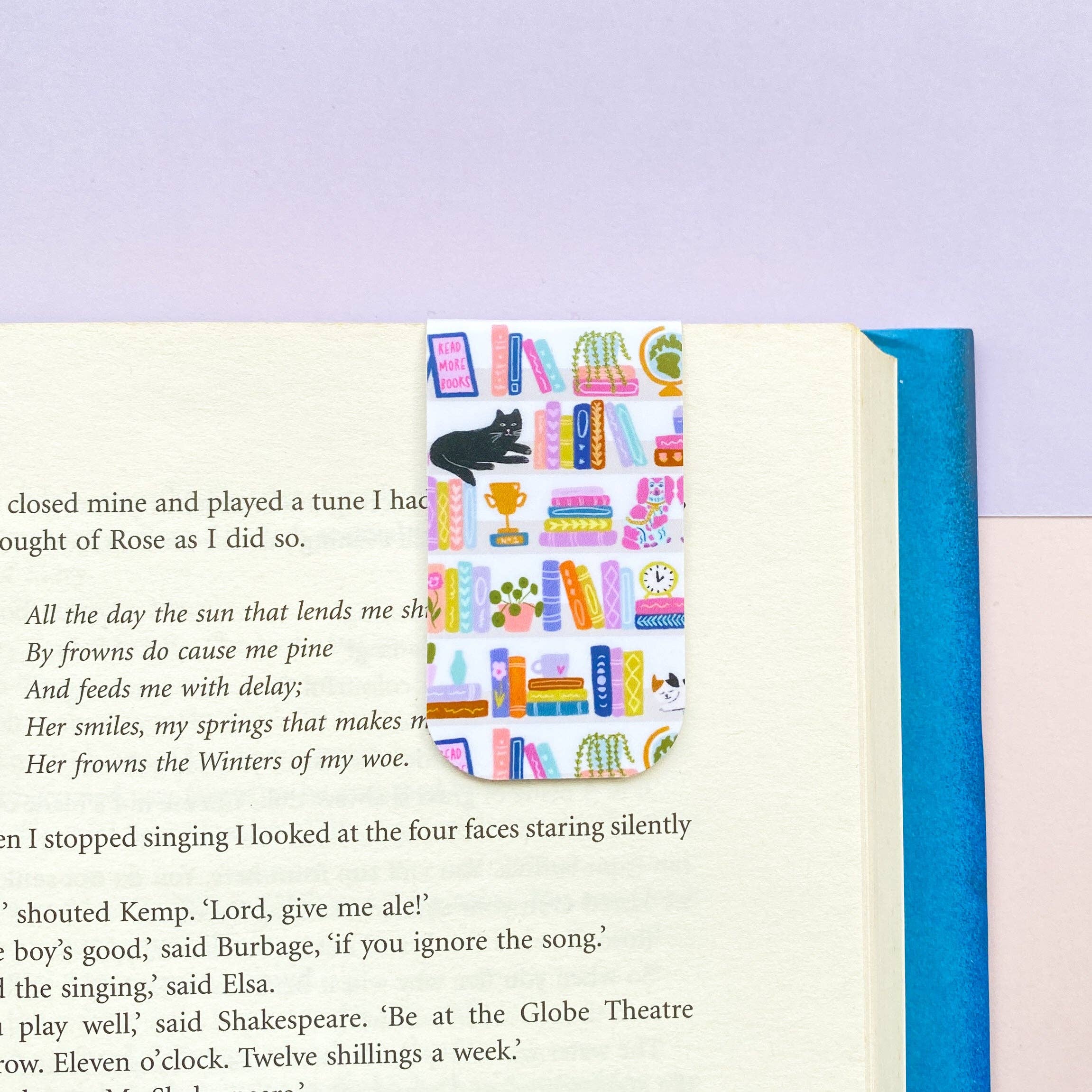 Open book with a colorful bookmark featuring books and a cat on a purple background