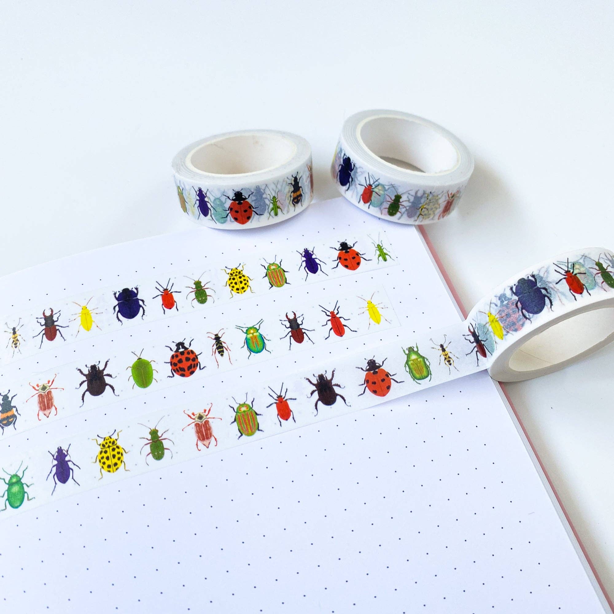 Two rolls of decorative tape with colorful bug designs on a white surface.
