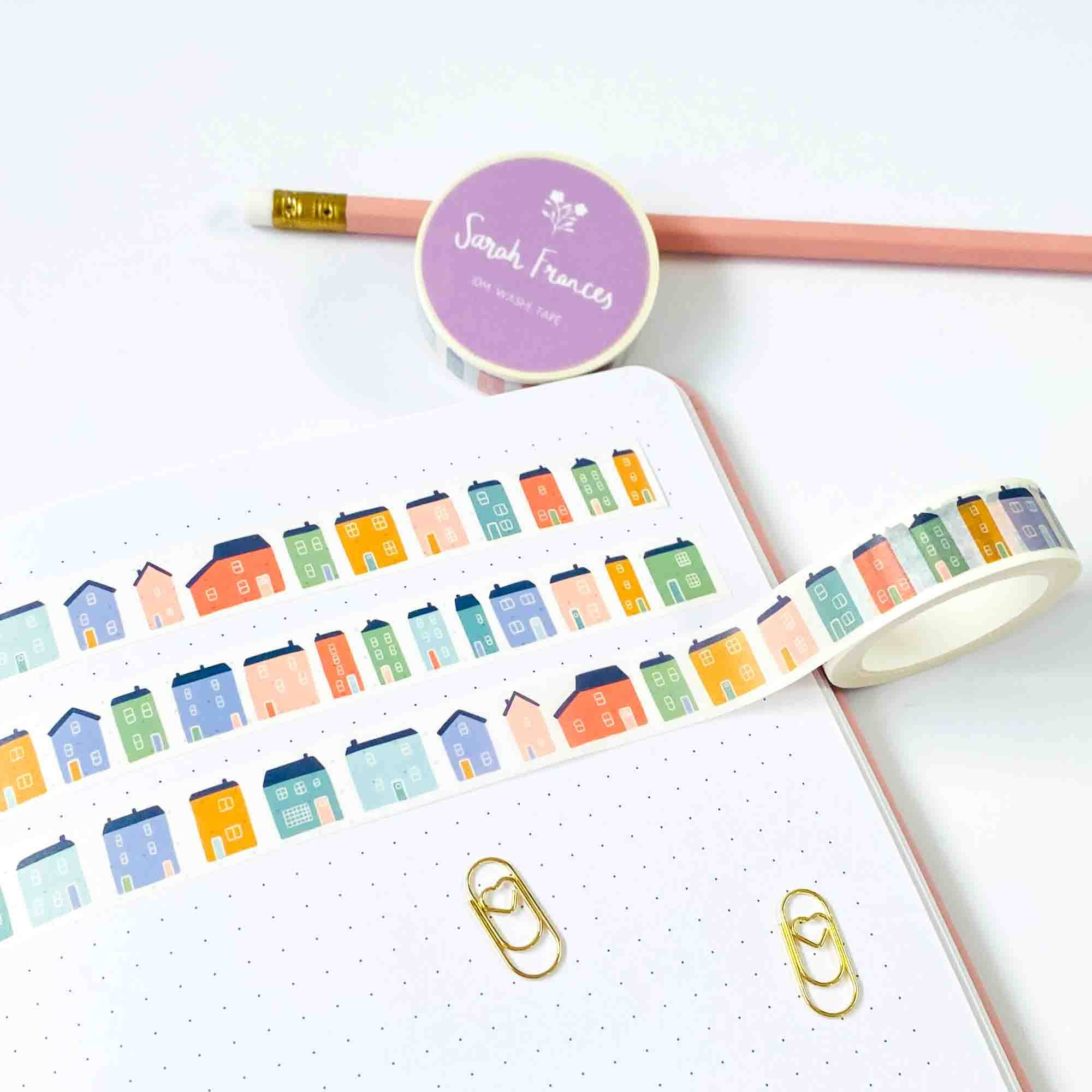 Colorful house-shaped stickers on a notebook with a pencil and washi tape.