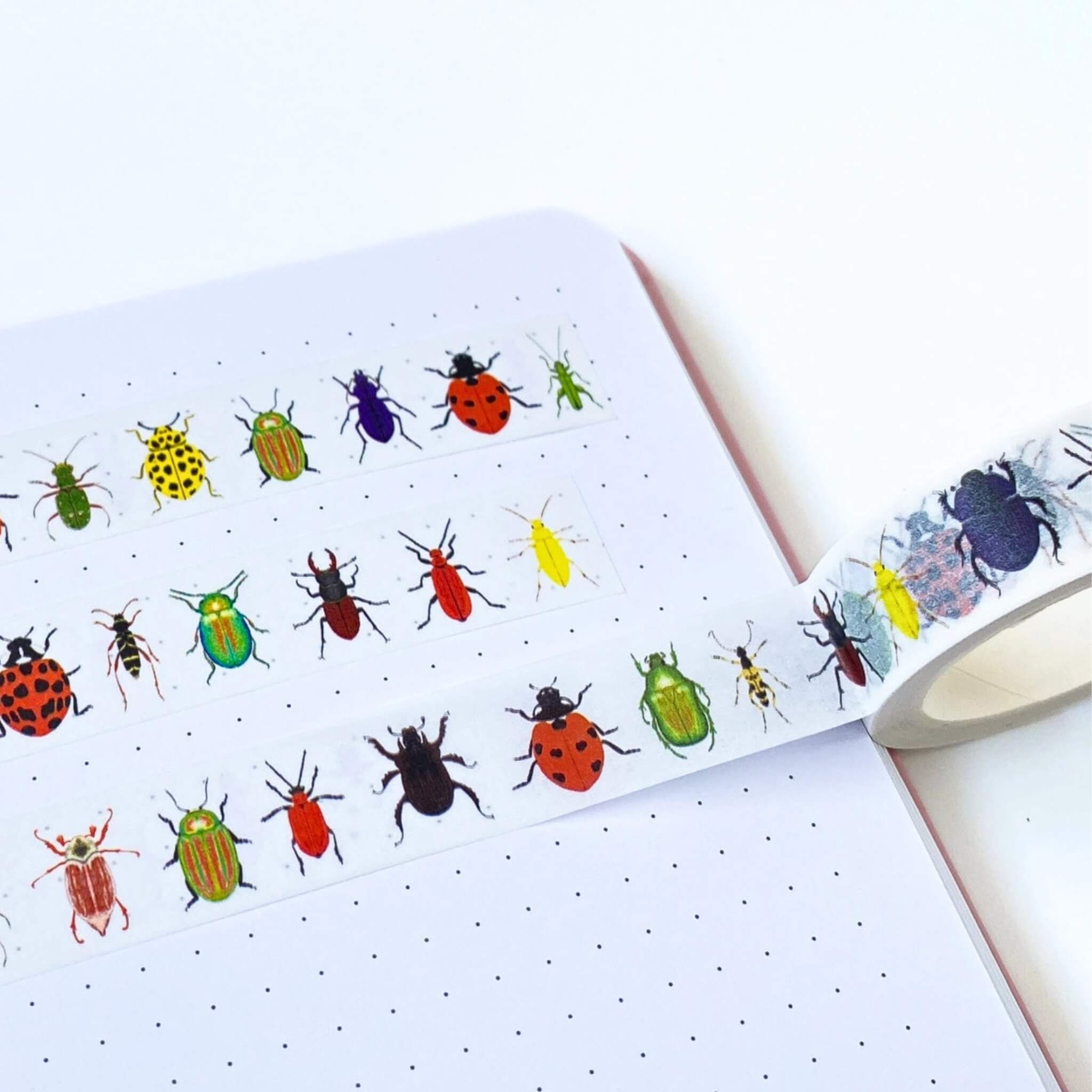 Colorful bug illustrations on a notebook with a pen.