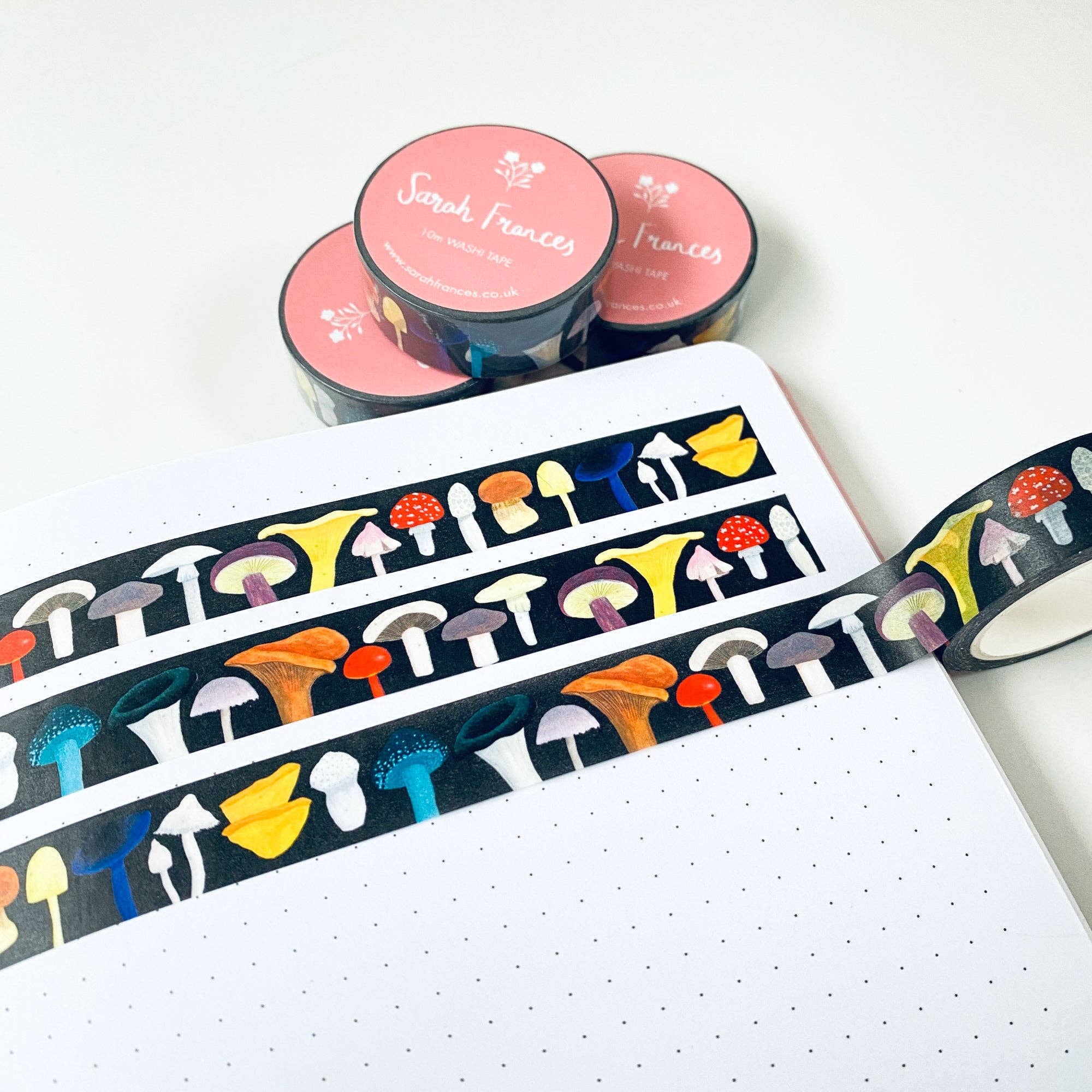 Colorful mushroom-patterned tape on a notebook with pink containers in the background