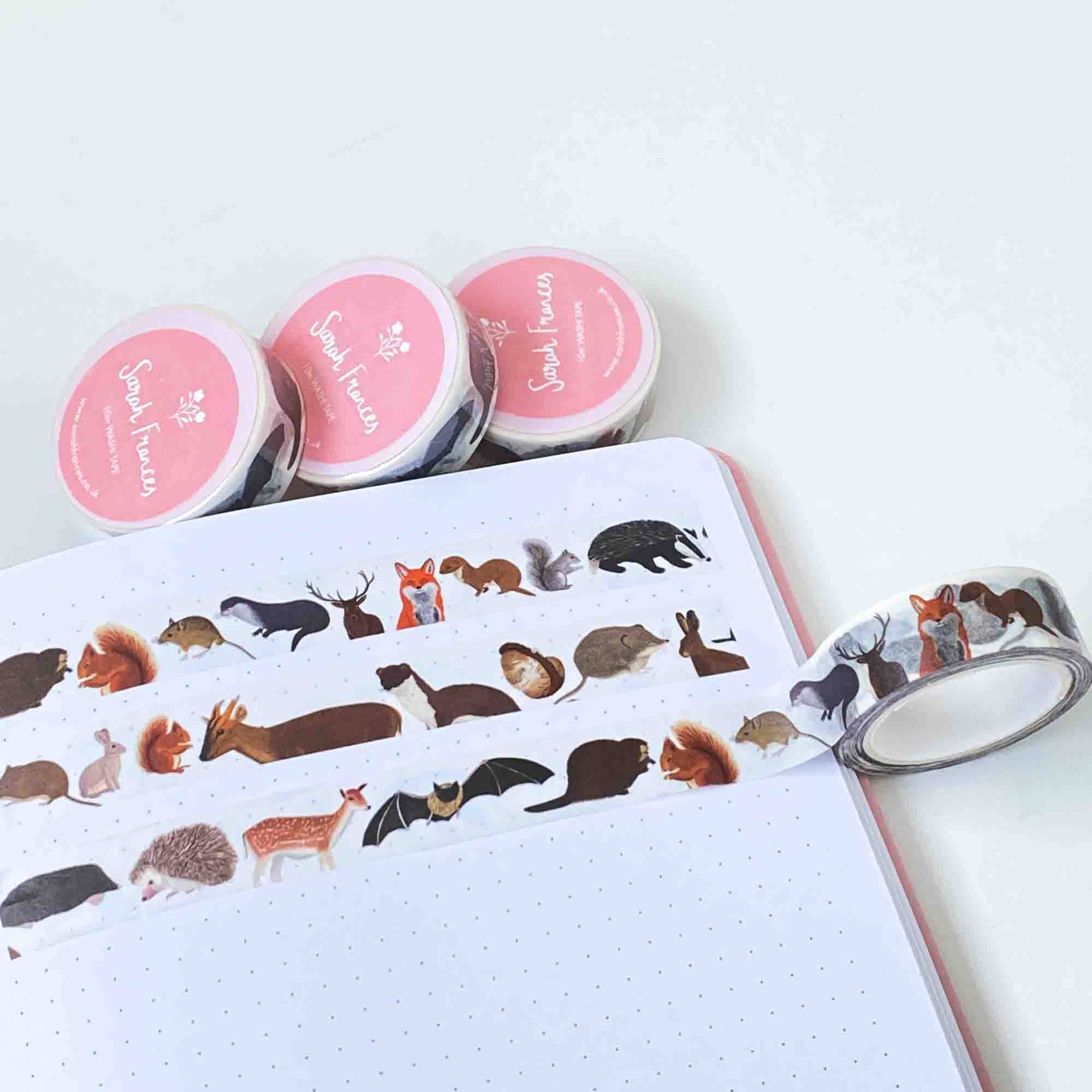 Set of animal-themed washi tape rolls on a notebook with a roll of tape on top.