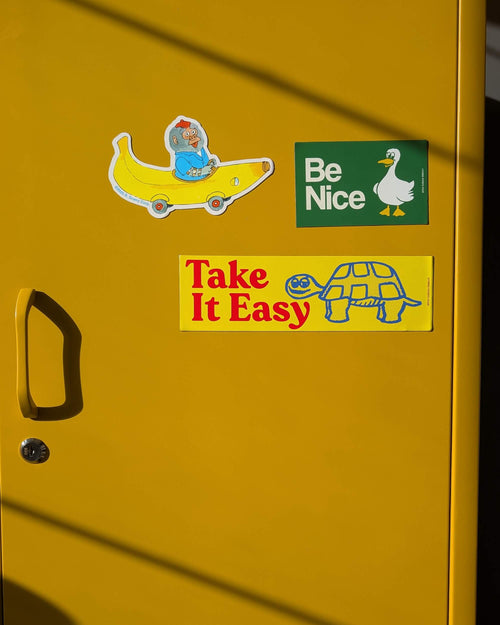 Yellow door with stickers including a turtle, banana character, and duck with 'Be Nice' text.