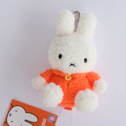 White plush miffy toy with an orange outfit on a white background