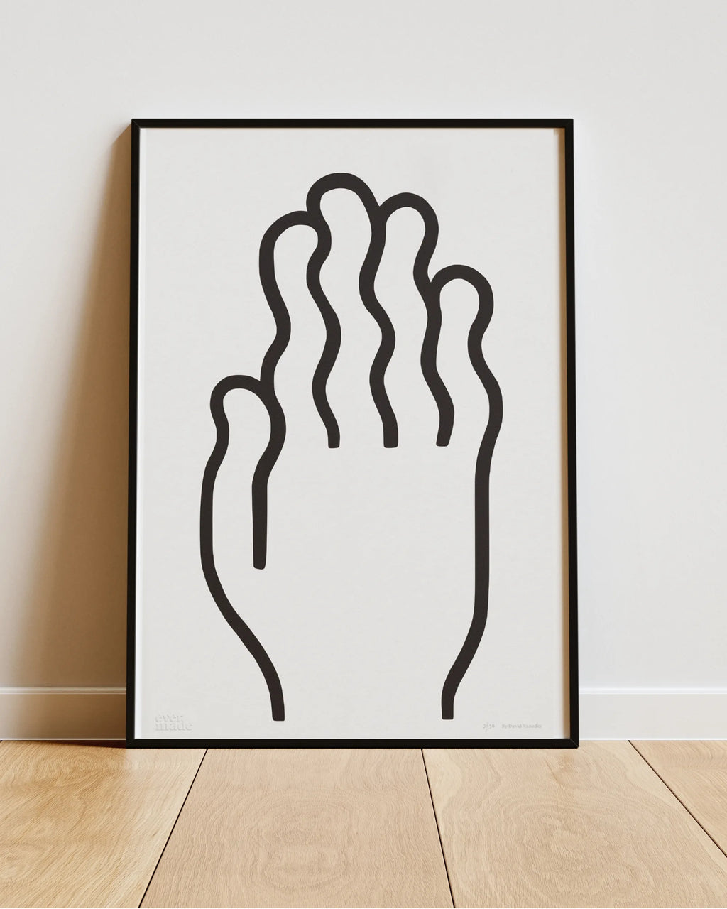Framed abstract artwork of a hand on a white wall.