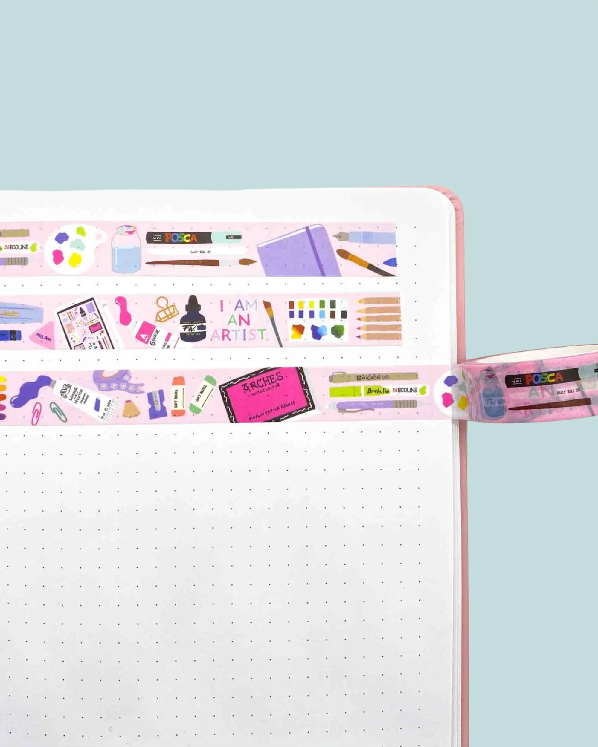 Decorative washi tape with various art supply designs stuck on a notebook page
