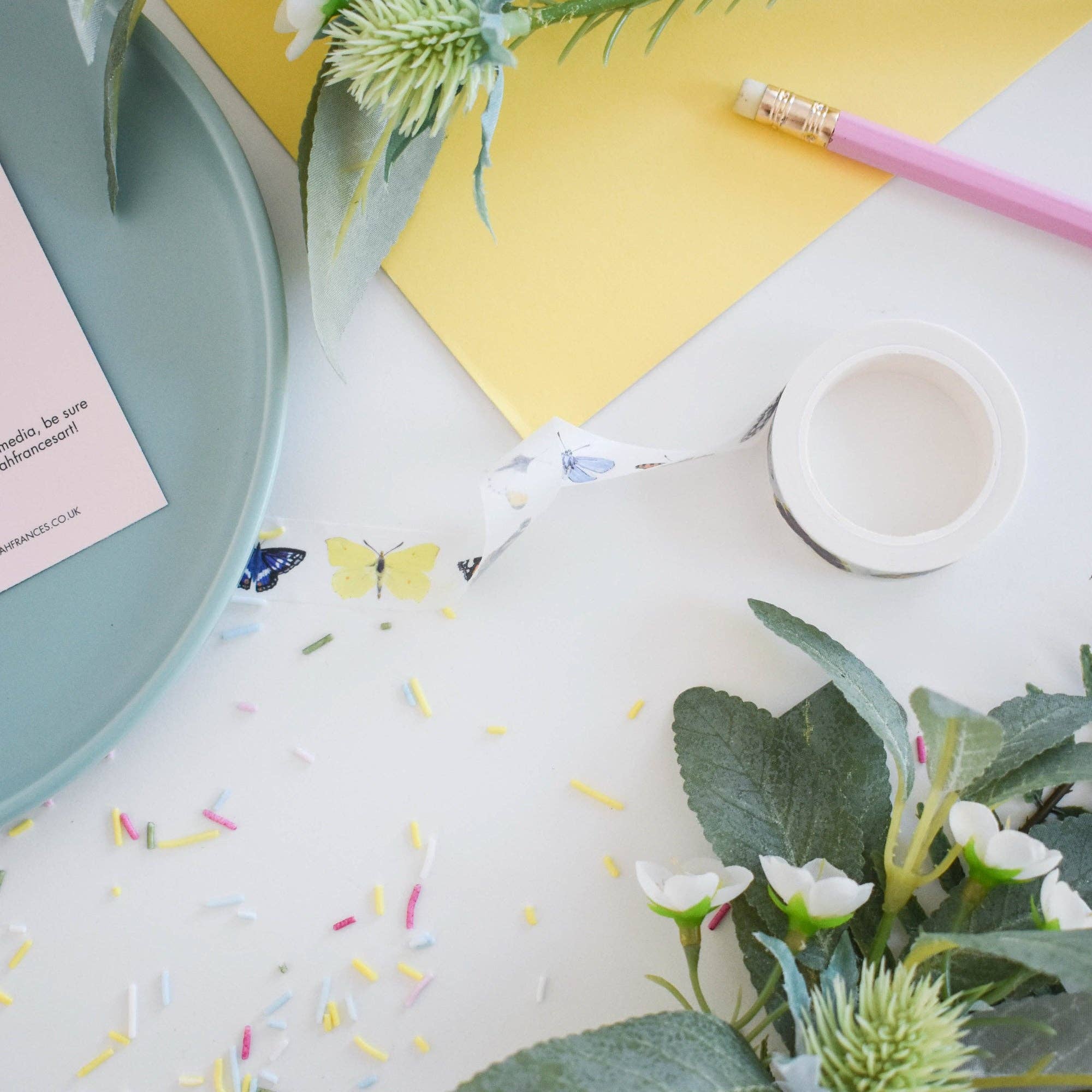 Desk with flowers, a pen, and colorful paper