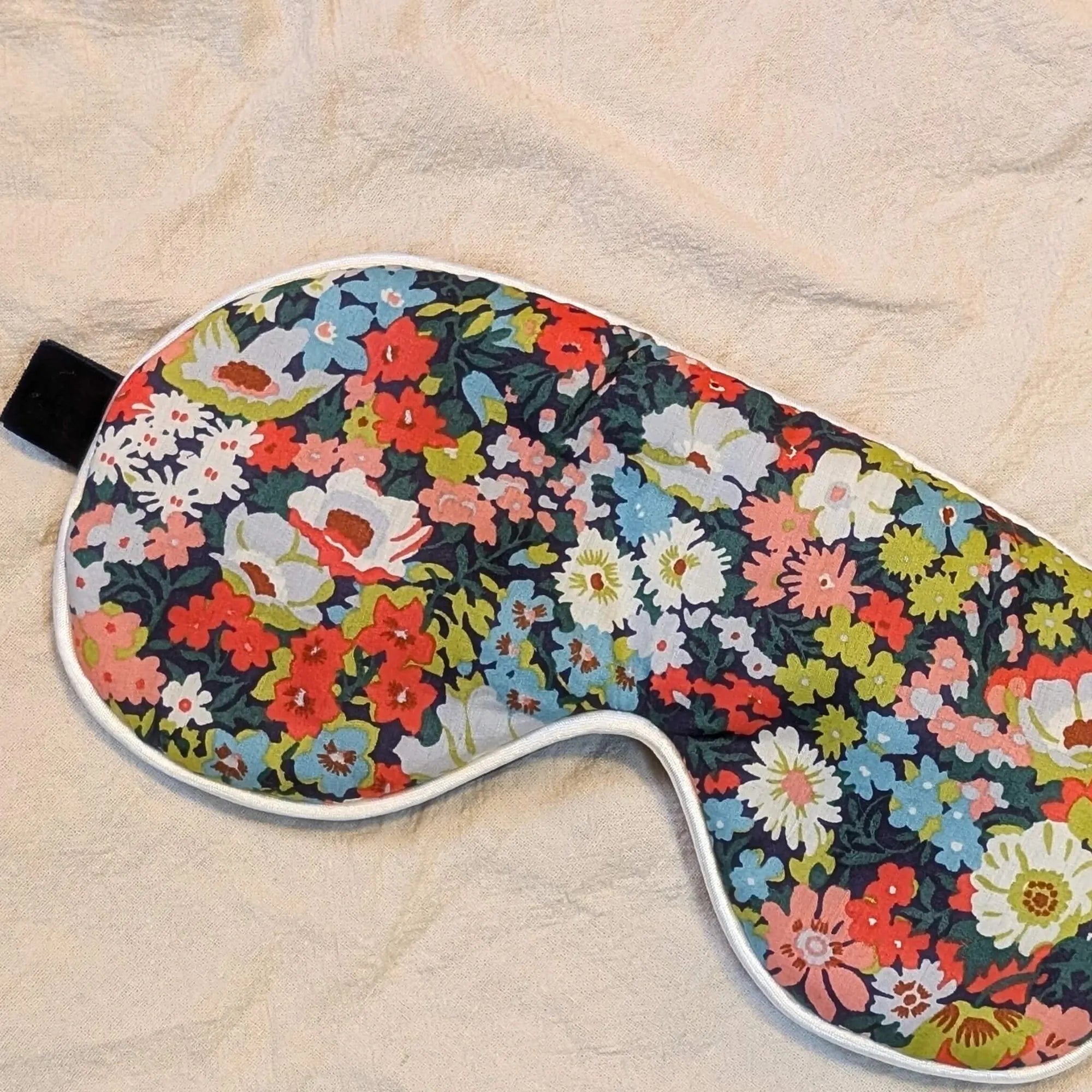 Floral patterned eye mask on a beige fabric background