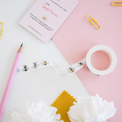 Stationery items including a pencil, washi tape, and a card on a pink background