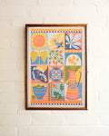Framed colorful artwork with floral and abstract designs on a white brick wall.