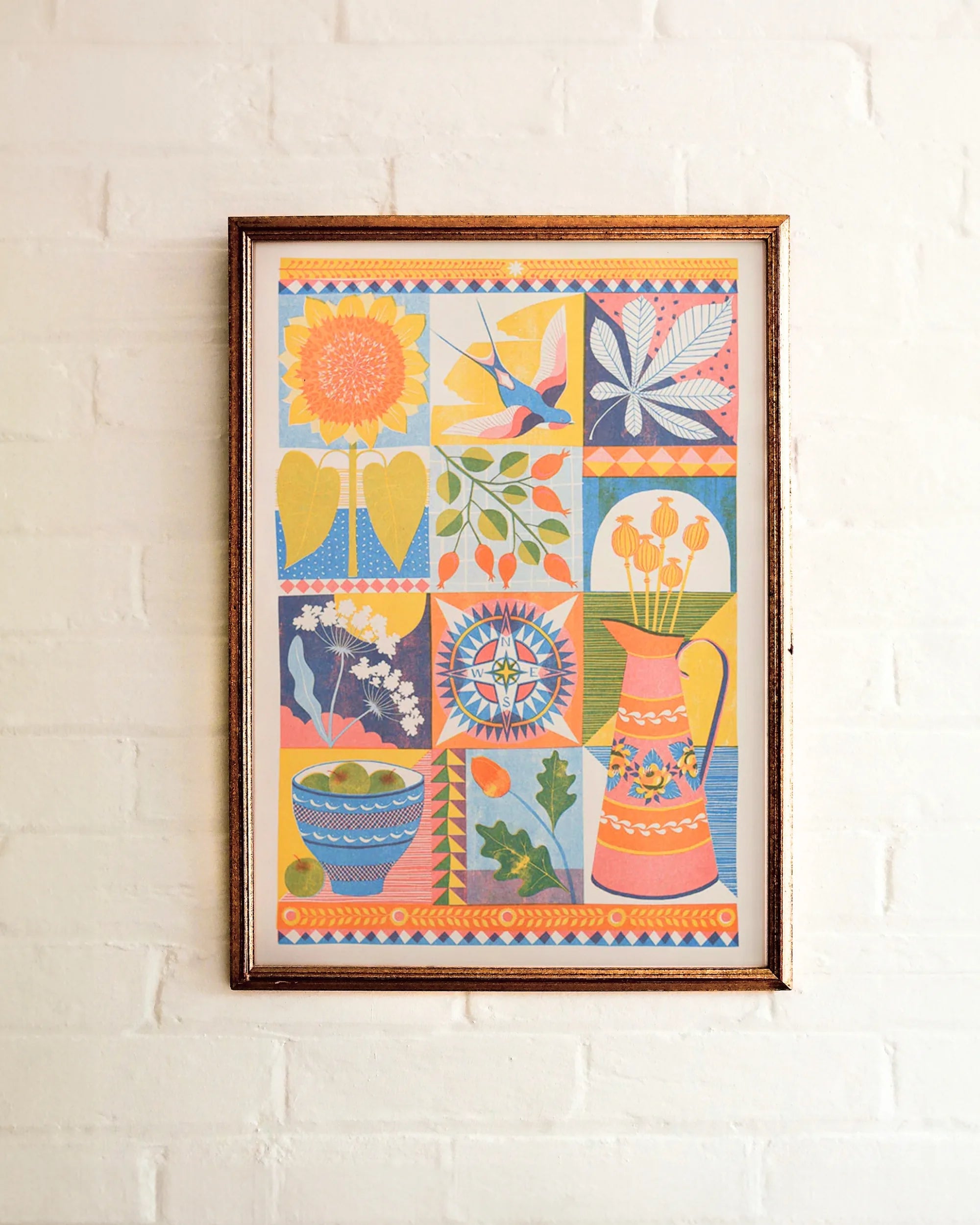Framed colorful artwork with floral and abstract designs on a white brick wall.