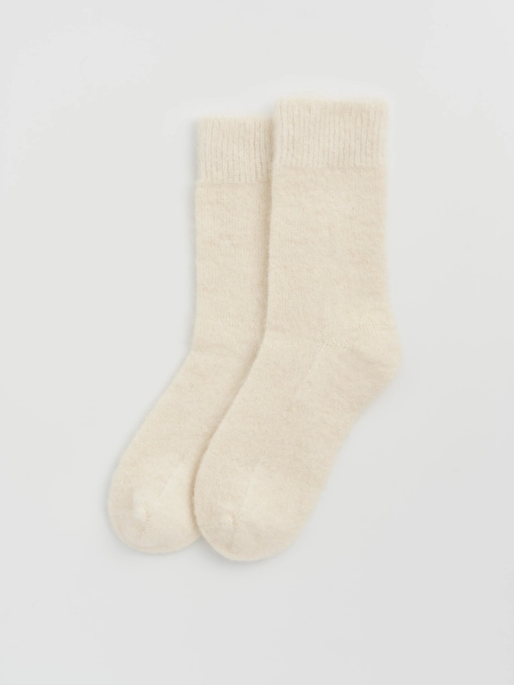 Pair of cream alpaca socks on a light gray background