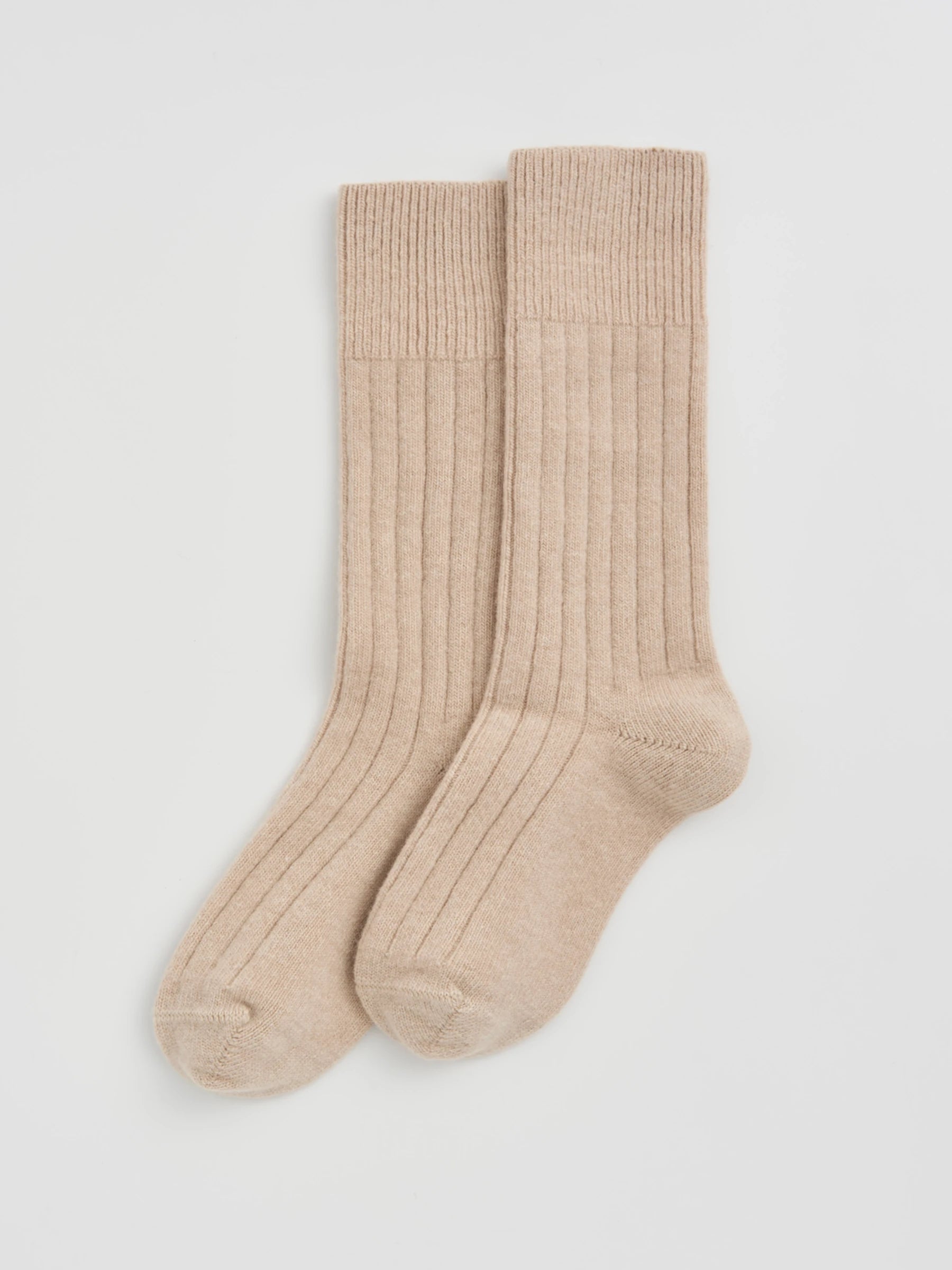 Pair of beige socks on a light gray background