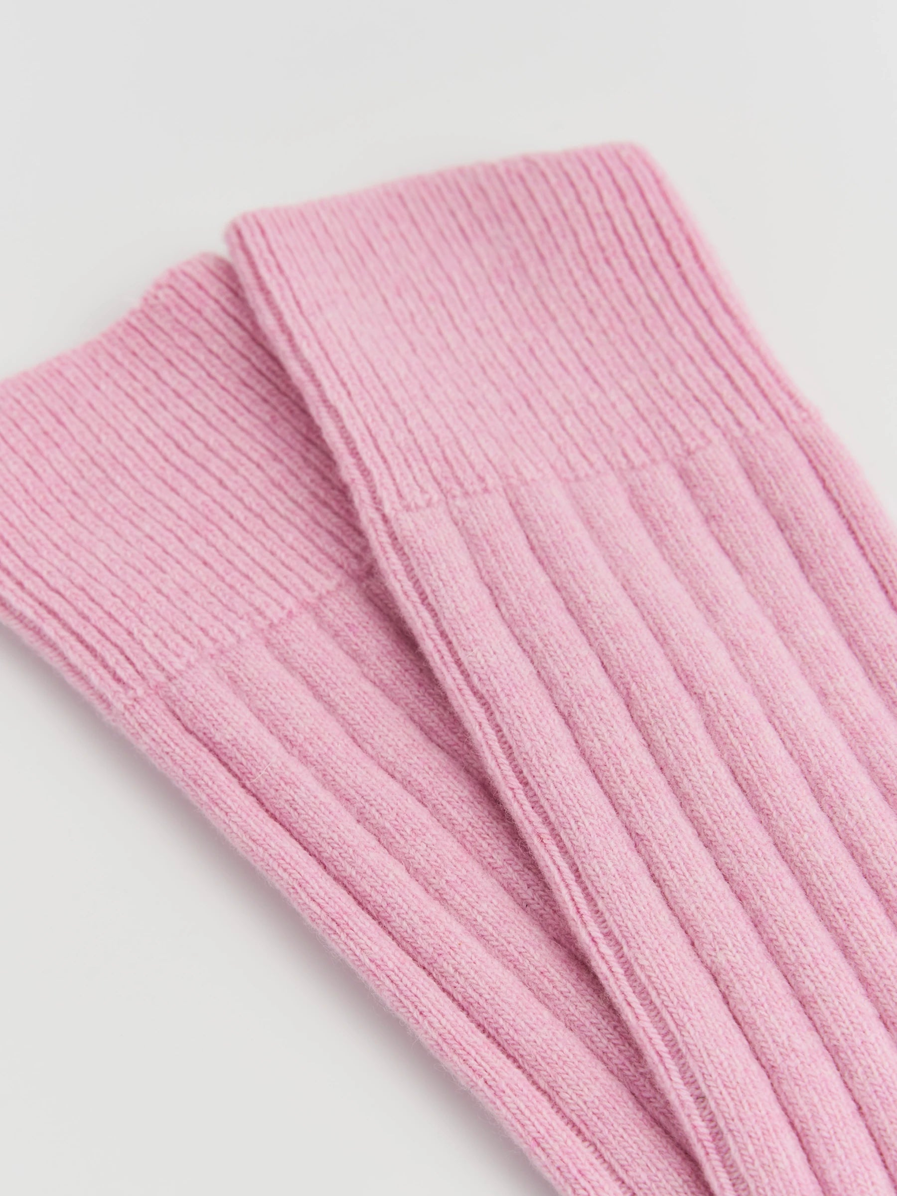 Close-up of pink ribbed knit socks on a light gray background