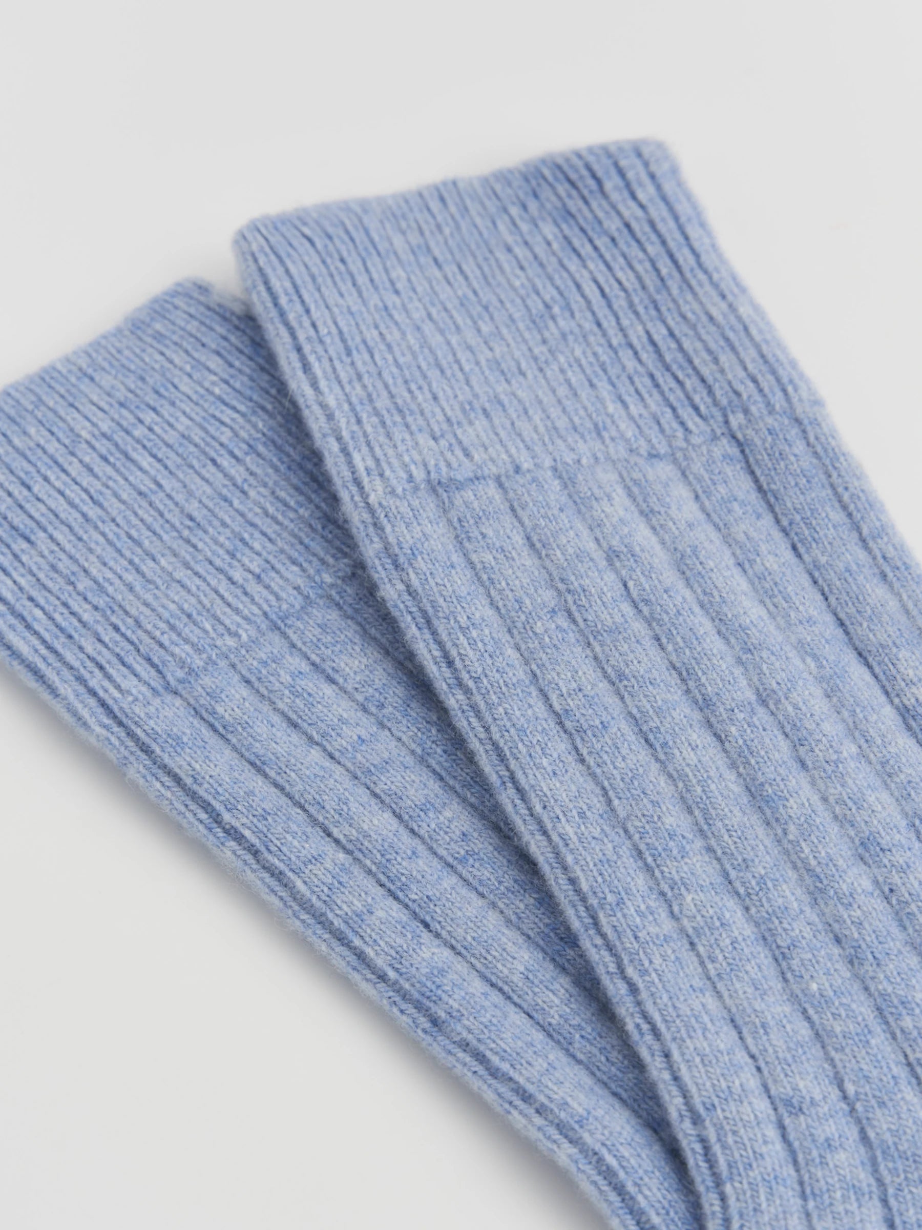 Pair of light blue ribbed socks on a light gray background
