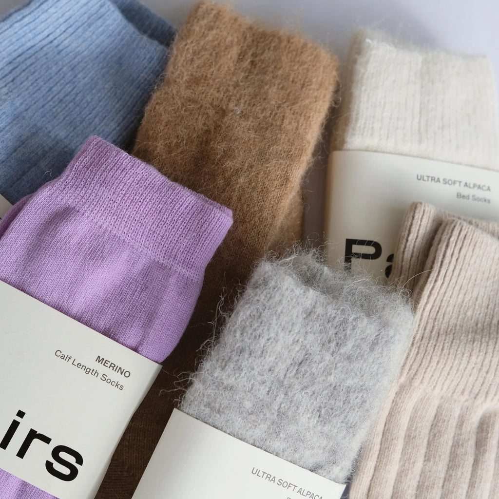 Collection of various colored socks with labels on a white background