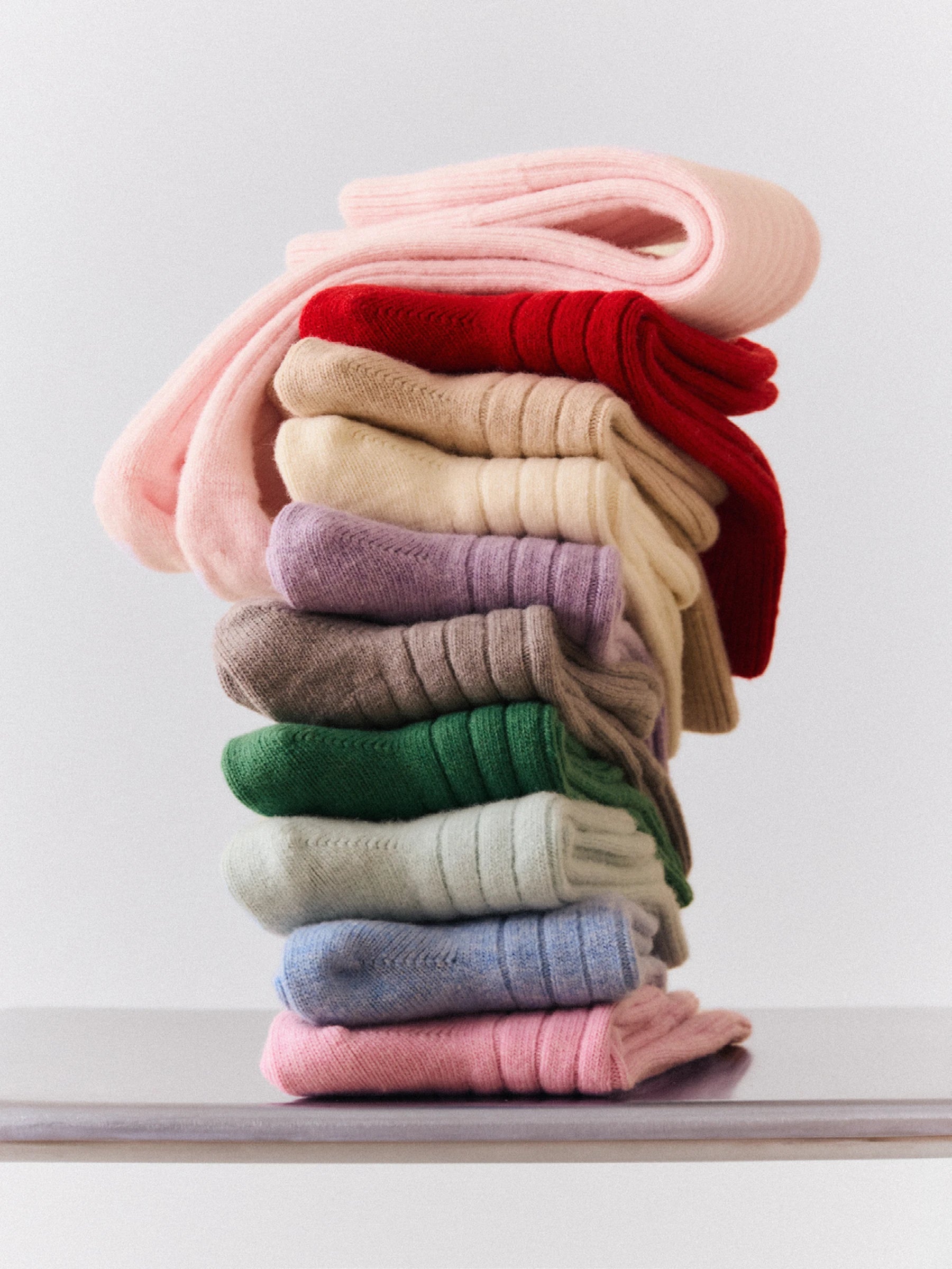 Stack of colourful wool merino socks on a white surface
