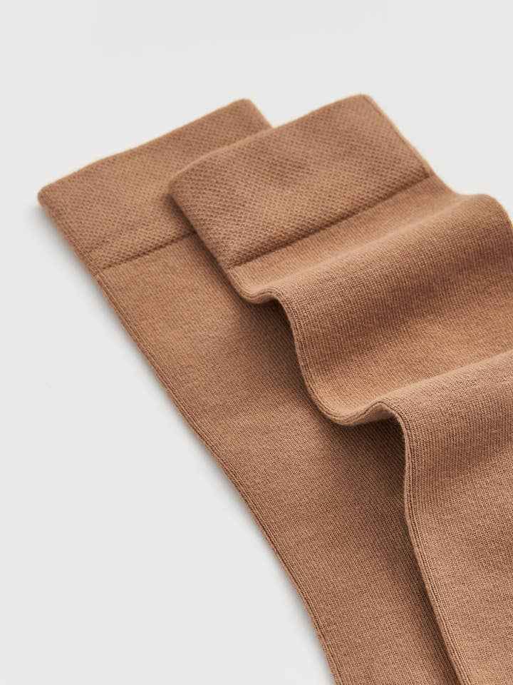 close up of bamboo socks in biscuit beige colour on a light gray background