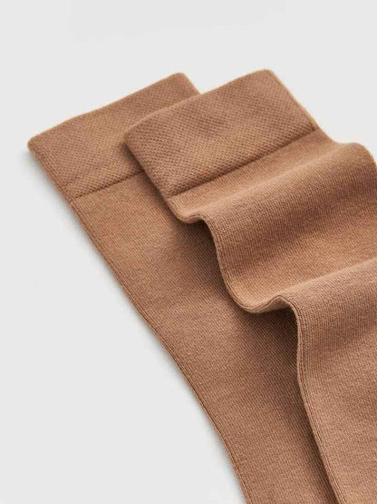 close up of bamboo socks in biscuit beige colour on a light gray background