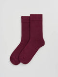 Pair of burgundy socks on a light gray background