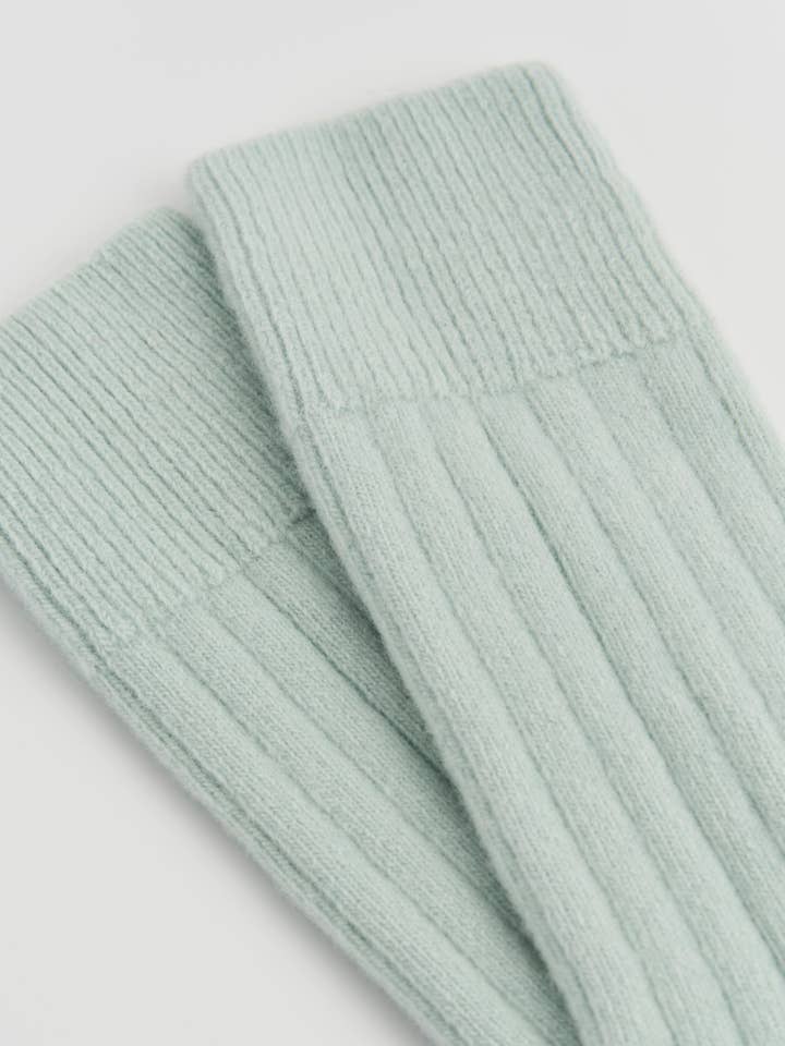 Light green ribbed knit socks on a light gray background