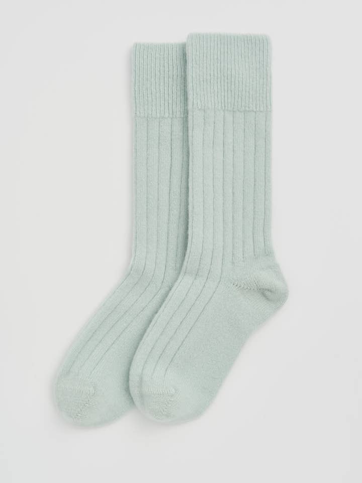 Pair of light green wool socks on a white background