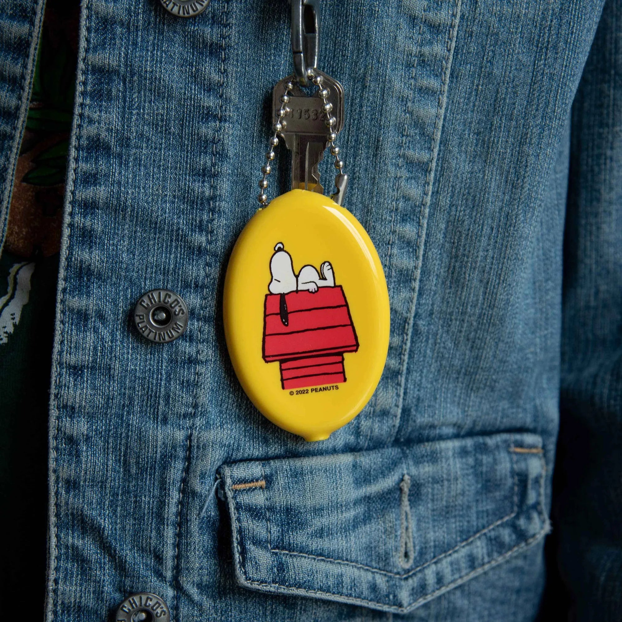 Yellow keychain with Snoopy design attached to a denim jacket