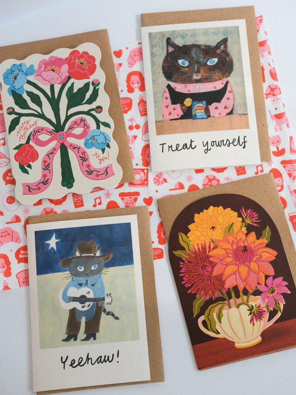 Four greeting cards with different designs on a patterned background