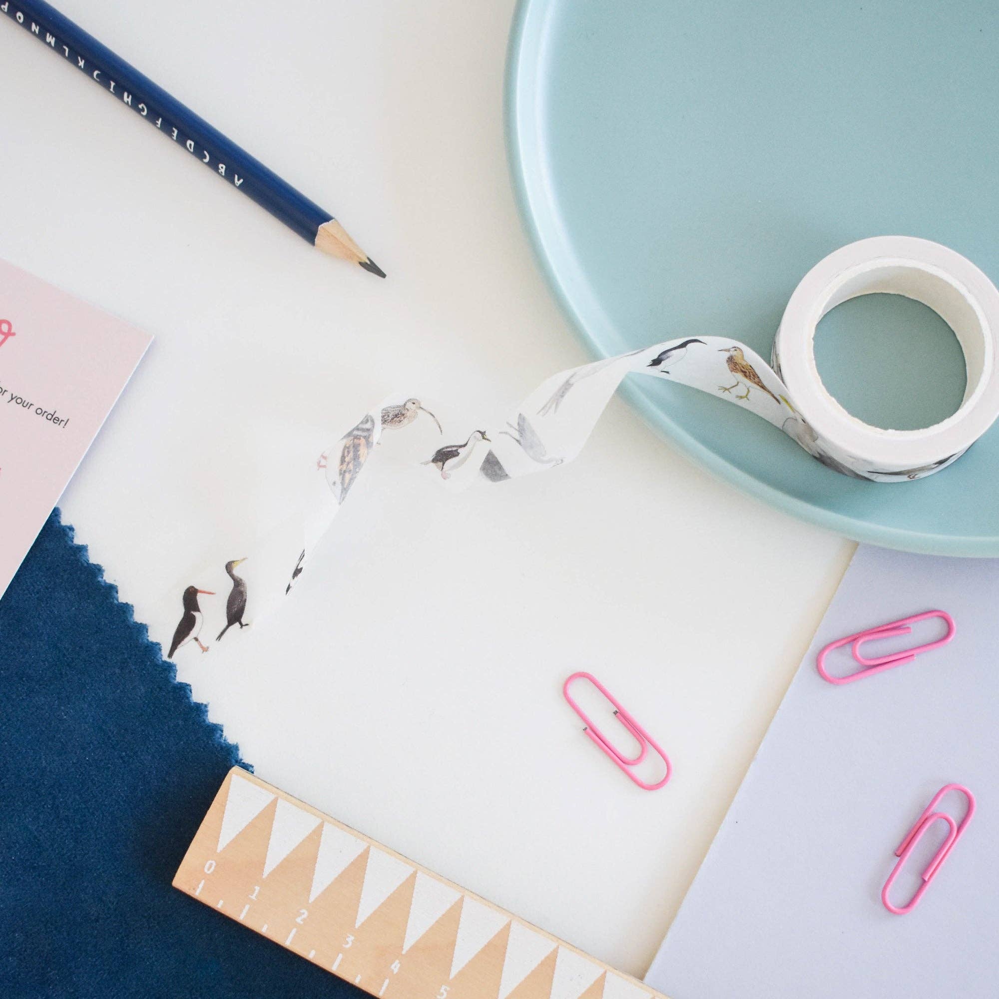 Stationery items including a pencil, tape, and paper clips on a white surface.